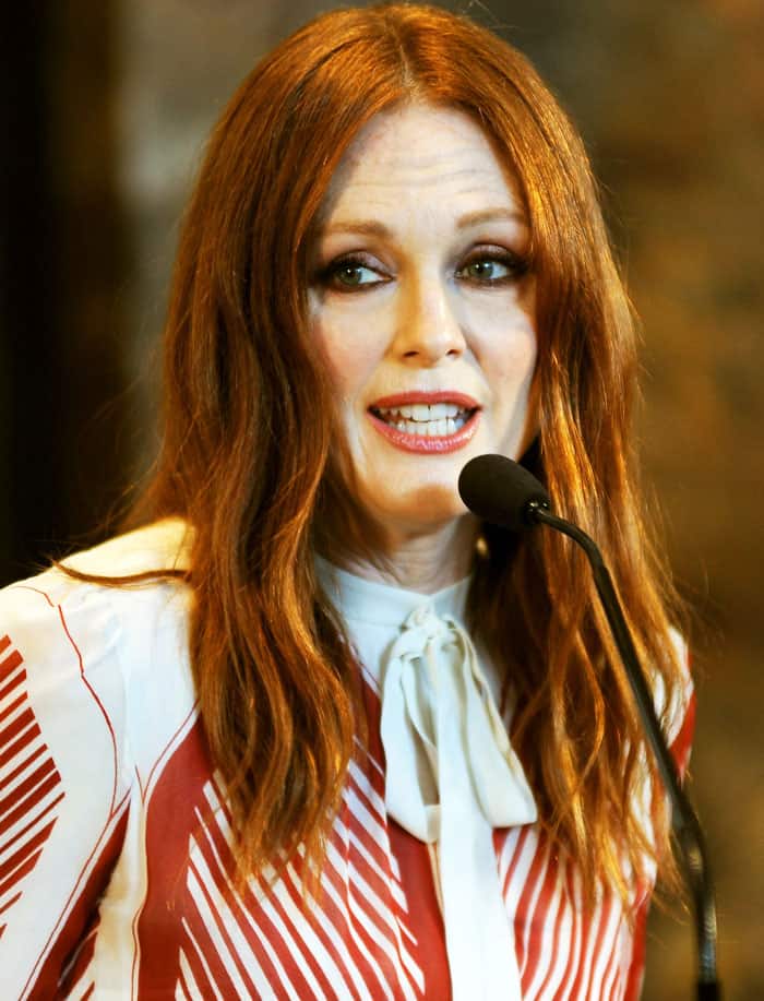Julianne Moore delivers a poised appearance with softly waved auburn hair, defined eye makeup, and a bow-tied neckline that reinforces the polished elegance of her red-and-white patterned look