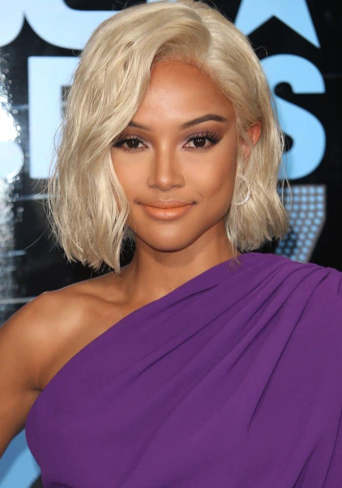 Karrueche Tran debuts a sleek platinum-blonde bob and luminous makeup, letting the saturated violet tone of her one-shoulder dress frame the look