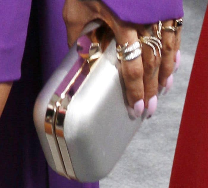 A pearl-toned clutch and stacked rings provide soft contrast against the bold purple fabric and metallic footwear