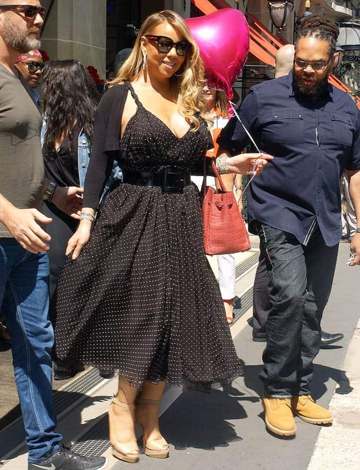 For her second Plaza Athénée departure in Paris on June 23, 2017, Mariah Carey softened her signature monochrome style with a flowing black polka-dot midi dress, nude platform sandals, and a reddish-brown crocodile Hermès Birkin