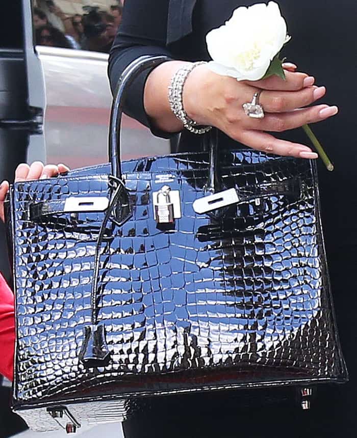 Mariah carried a glossy black crocodile Hermès Birkin 30, pairing the iconic handbag with a white rose and the 35-carat diamond engagement ring she received from former fiancé James Packer