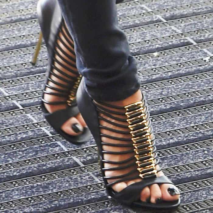 A close-up reveals the architectural drama of the heels, with elasticated straps and gold hardware drawing the eye straight to her feet
