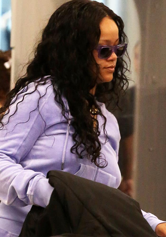 Rihanna goes for a casual yet chic airport look in a lavender hoodie paired with statement sunglasses as she passes through LAX
