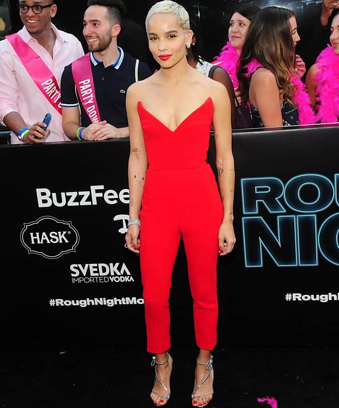 Zoë Kravitz lights up the Rough Night premiere in a bold red Oscar de la Renta jumpsuit, paired with shimmering silver “Romy” sandals that elongate her frame