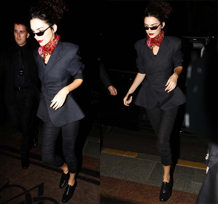 Kendall Jenner sports an all-black Jacquemus pantsuit, elevated by a vibrant Gucci floral scarf and classic Manolo Blahnik oxfords at the Miu Miu presentation