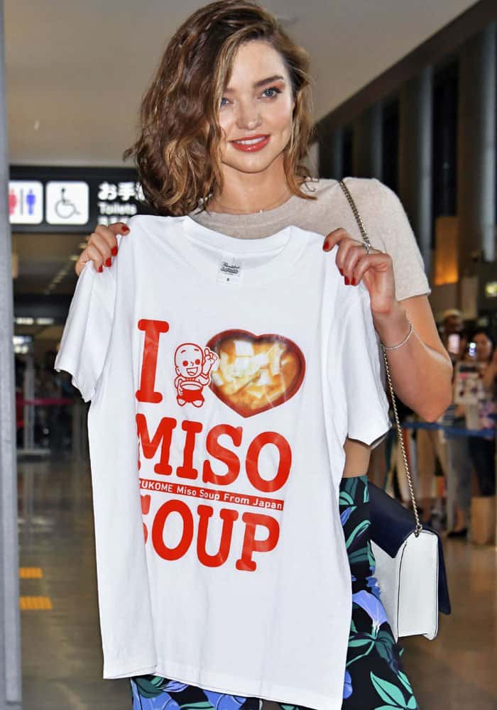 Showing her appreciation for a fan, Miranda Kerr holds up a 'I Love Miso Soup' t-shirt she received upon her arrival in Tokyo