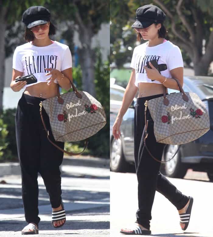 Vanessa Hudgens pairs black-and-white Adidas Adilette slides with relaxed black pants, a cropped "Feminist" tee, and an embroidered Gucci GG Supreme tote