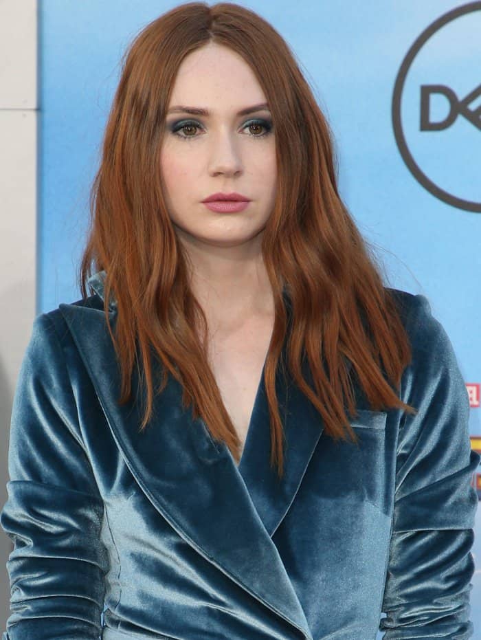 Karen Gillan wore her signature auburn hair in soft, tousled waves and complemented her blue velvet look with smoky eyeshadow and a muted rose lip for a modern, moody finish