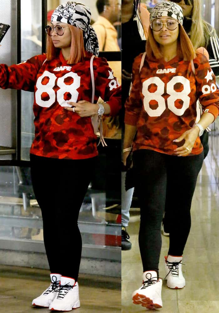 Blac Chyna is shown in a casual streetwear outfit, featuring a BAPE camouflage top, black leggings, and white sneakers