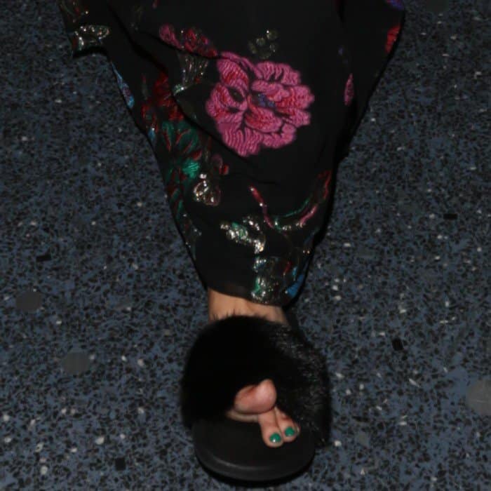 Jessica Simpson's teal pedicure peeks through as her toe slightly slips out of her black fur slide sandal