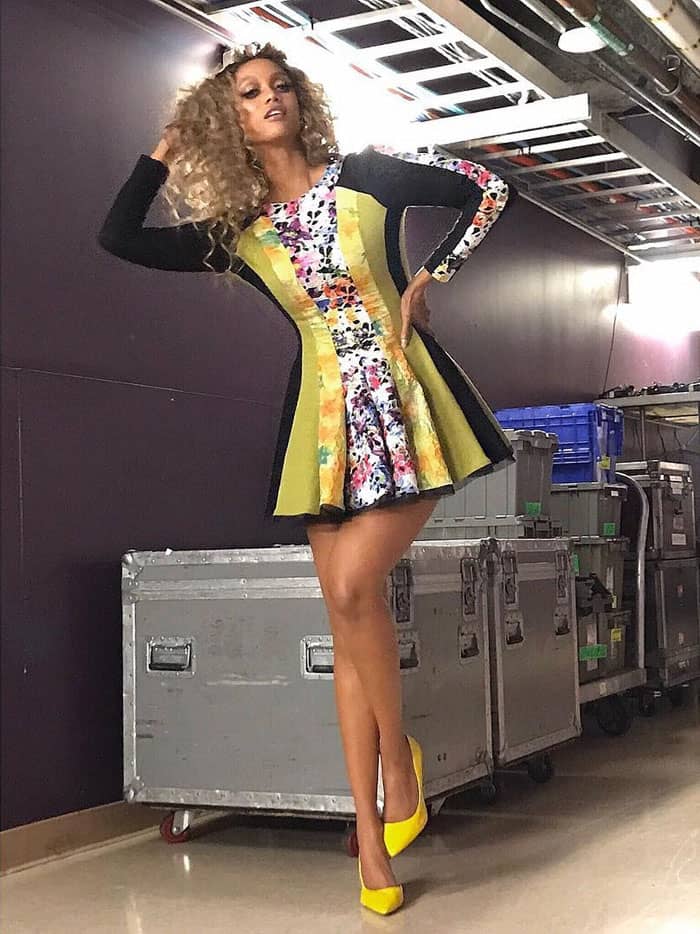 Tyra Banks strikes a pose backstage in her Instagram post, flaunting her playful multi-print dress and bold yellow heels, captioning the moment with confidence as she hosts the number one show on TV.