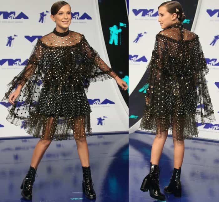 Millie Bobby Brown shows off her embellished Rodarte Spring 2017 tulle dress paired with glossy black Stuart Weitzman “Climbing” boots on the MTV VMAs blue carpet