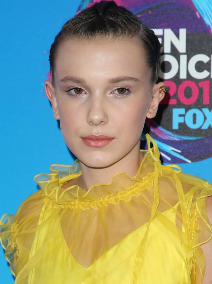 In a tighter beauty shot, her slicked-back braids, soft pink makeup, and understated earrings keep the focus firmly on the dress’s texture