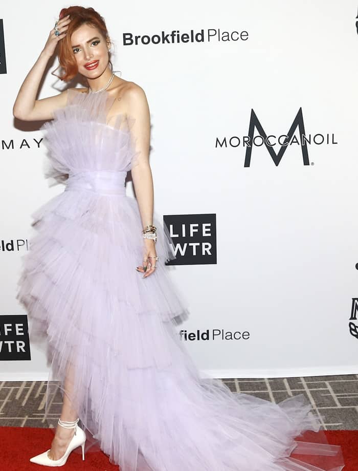 Posing front-on, Bella highlights the gown’s layered tulle bodice and cinched waist, pairing the ethereal silhouette with sleek white ankle-tie pumps