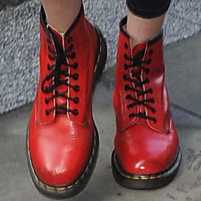 Gigi Hadid's bright red Dr. Martens boots provide a bold design statement with their iconic yellow stitching and robust sole, complementing her Tommy Hilfiger ensemble
