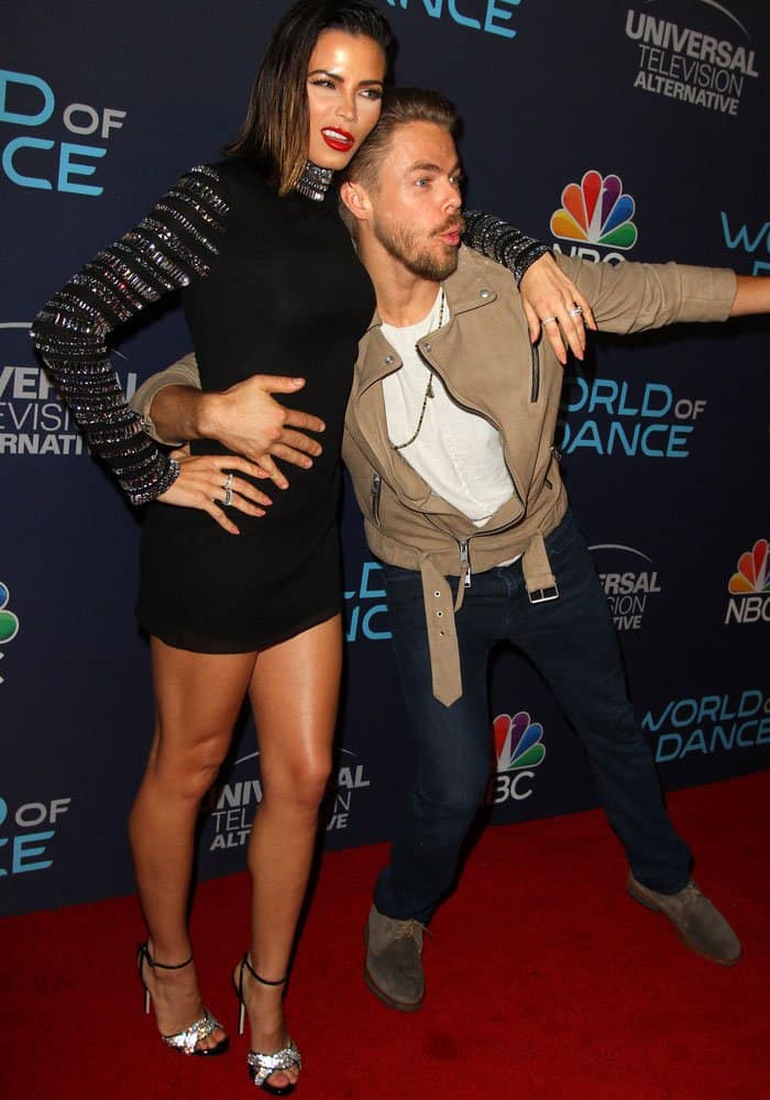 Jenna playfully poses with fellow World of Dance judge Derek Hough while showing off her glittering heels and Azzaro dress