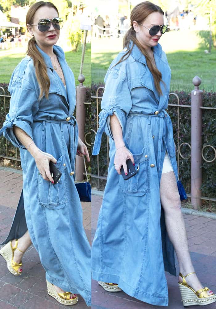 Lindsay Lohan pairs her knotted-sleeve denim wrap dress with gold Gucci “Barbette” espadrille wedges, effortlessly blending casual cool with high-end flair