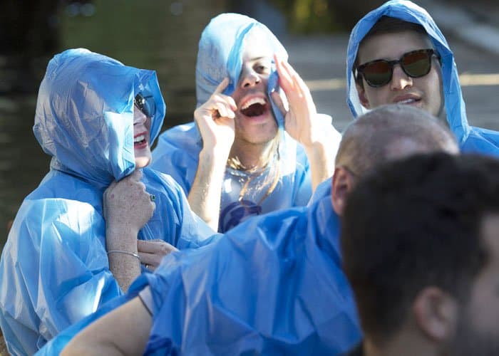 Lindsay Lohan shares a laugh with friends while staying dry in a blue waterproof poncho before the ride kicks off