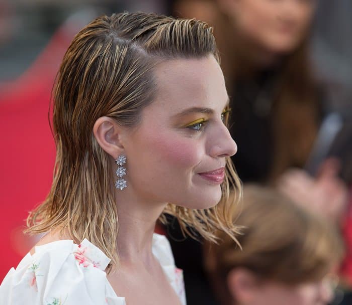 Margot Robbie completed her romantic premiere look with sparkling floral drop earrings and softly glowing makeup