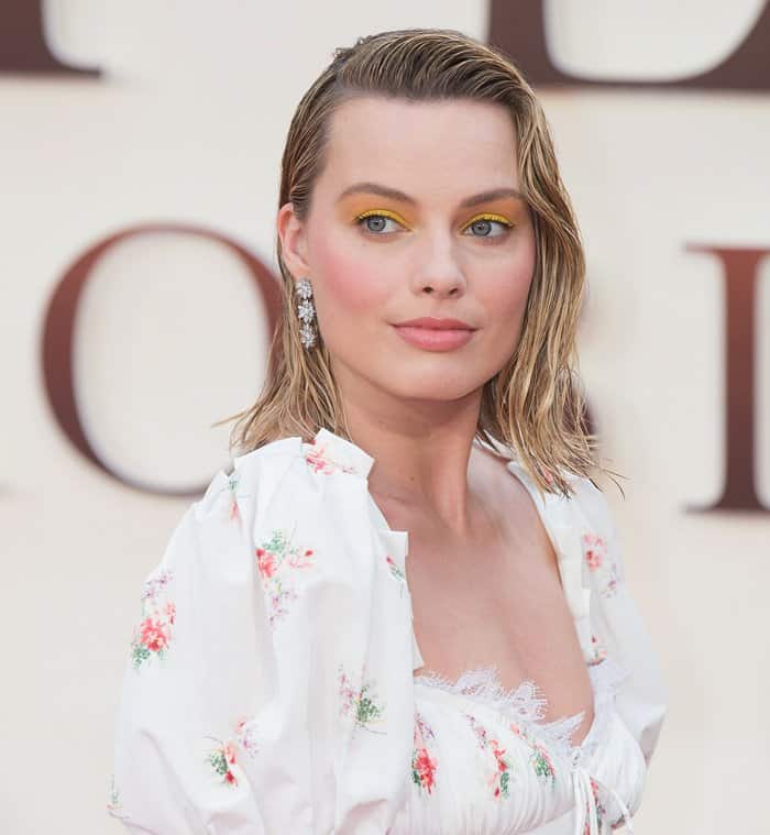 Margot Robbie paired slicked-back wet-look hair and bold yellow eye makeup with diamond floral earrings