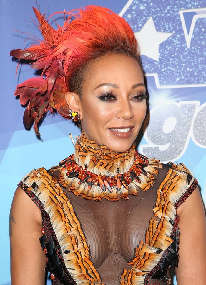 Mel B pairs her bold feathered hairstyle with a sheer, embellished minidress featuring tiger-striped detailing and a jeweled neckline