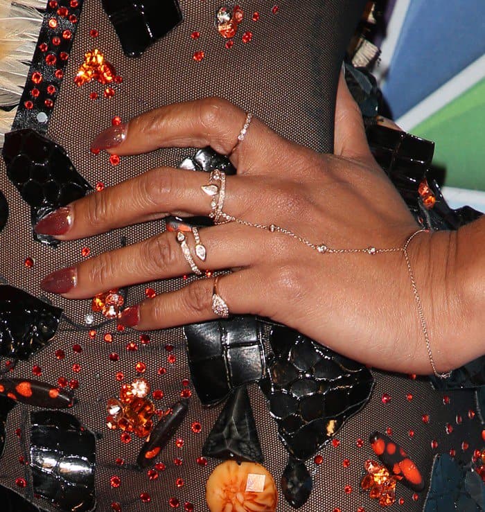 Mel B’s hands sparkle with layered diamond rings that complement the orange and black embellishments on her dress