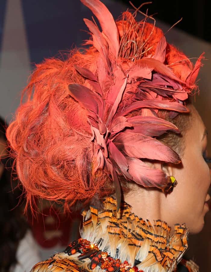 A side view reveals the intricate cluster of burnt-orange feathers woven into Mel B’s vibrant updo