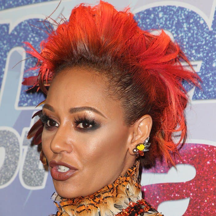 Mel B debuts fiery orange hair styled in a dramatic, feather-accented mohawk for the AGT semi-finals red carpet