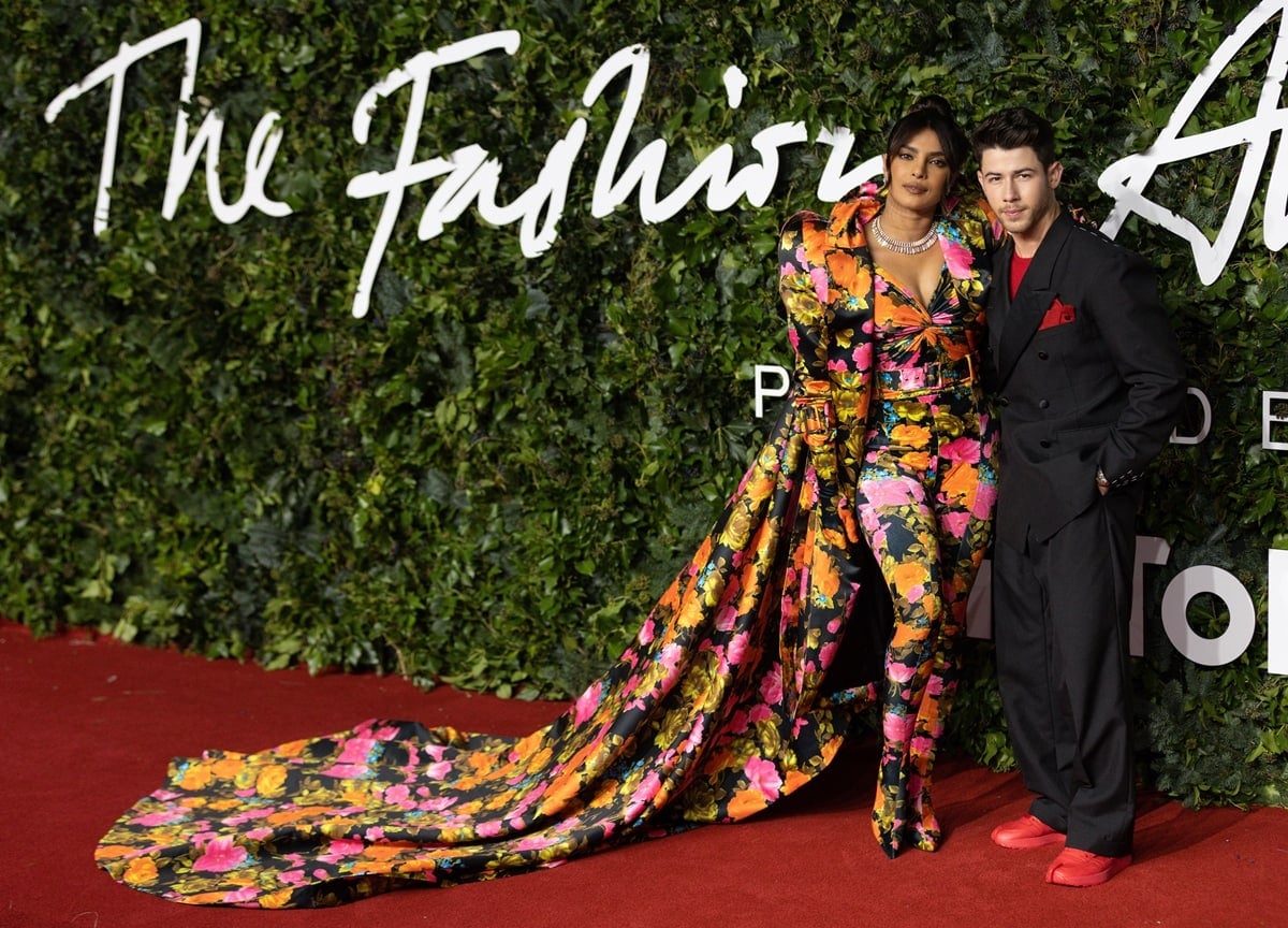 Priyanka Chopra's sweeping Richard Quinn floral train stretched across the red carpet while Nick Jonas contrasted her maximalist couture in an oversized Maison Margiela tuxedo with bright red Maison Margiela x Reebok Tabi sneakers at The Fashion Awards in London