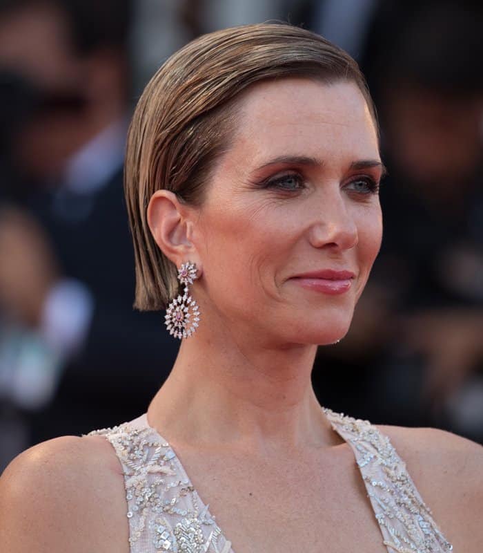 Kristen Wiig exudes sophistication with her slicked-back hair, radiant makeup, and dazzling Buccellati drop earrings