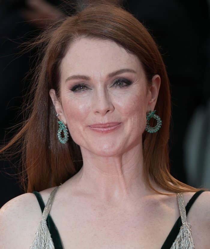 Julianne Moore exudes elegance with sleek, straight hair, soft pink makeup, and striking emerald Chopard earrings