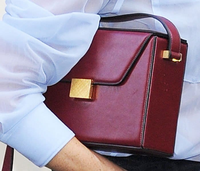 The former pop star contrasts her ruffled skirt with a structured vanity cross body bag in bordeaux red