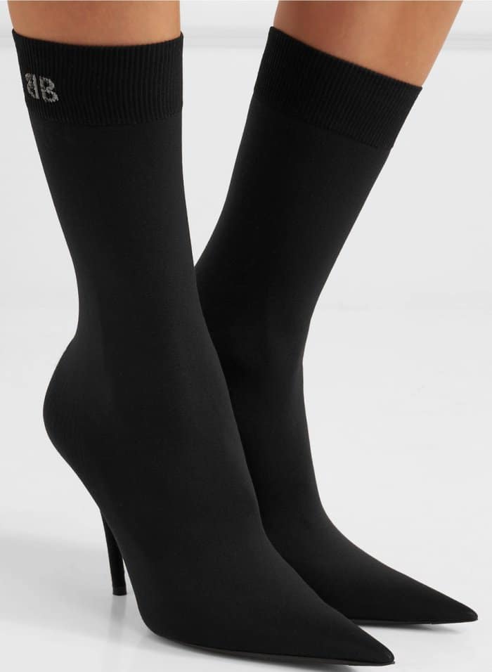 Balenciaga’s black stretch-jersey sock boots feature the brand’s signature knife-sharp pointed toe, a slim stiletto heel, and a ribbed cuff embroidered with the BB logo