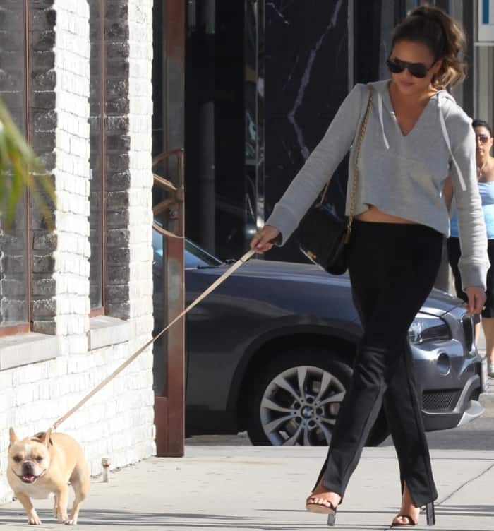 Chrissy Teigen keeps her look laid-back and polished in a gray cropped hoodie and slit-hem pants as she strolls with Pippa in Los Angeles