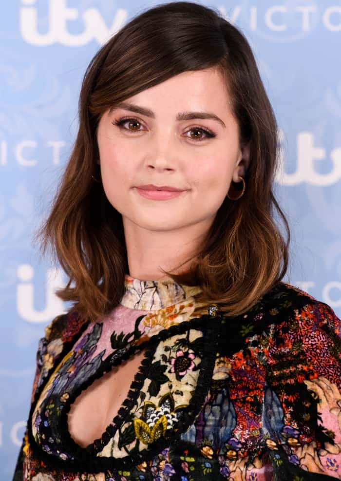 Jenna Coleman kept her beauty look understated with softly waved hair, natural makeup, and delicate gold hoop earrings that allowed the intricate Erdem print to remain the focal point