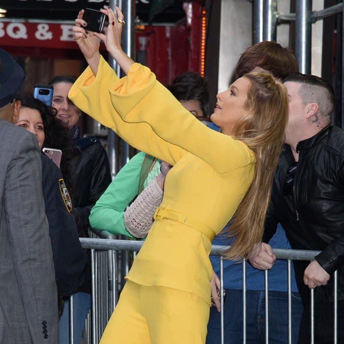Blake Lively greets fans outside Good Morning America in New York City, lifting her phone for a selfie while wearing a canary-yellow Brandon Maxwell Spring 2018 look