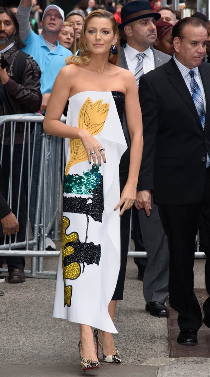 Blake Lively walks curbside amid fans and security, revealing the column silhouette of her Oscar de la Renta look paired with statement heels