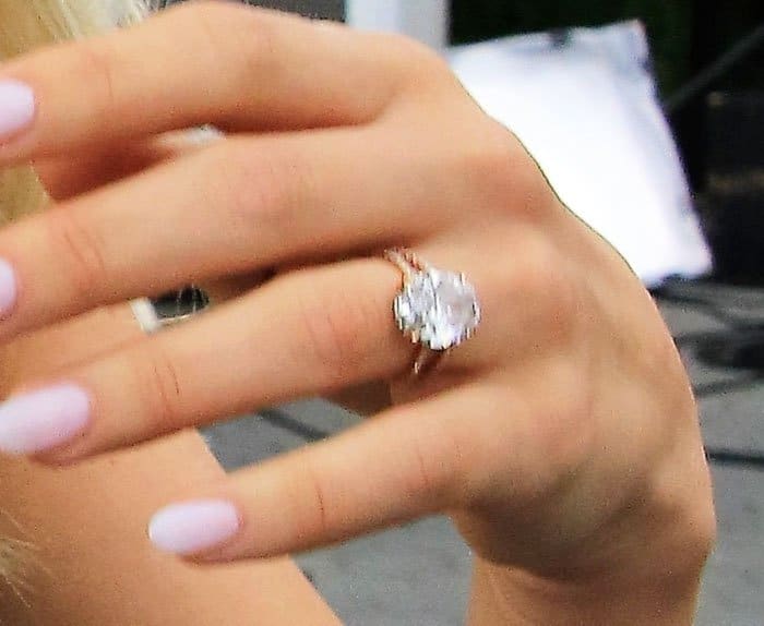 A close-up highlights Julianne’s rose-gold engagement ring and soft pink manicure during her appearance