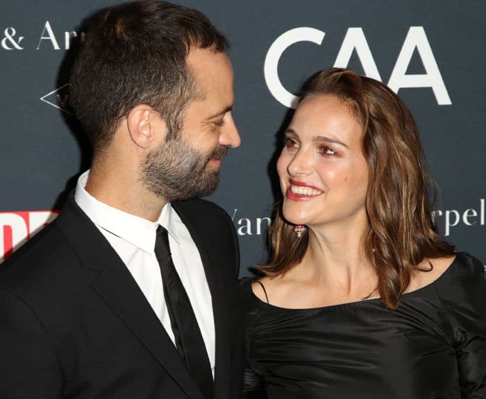 Natalie Portman shares a warm red-carpet moment with husband Benjamin Millepied, her softly draped Dior dress and delicate earrings reinforcing the understated elegance of the evening