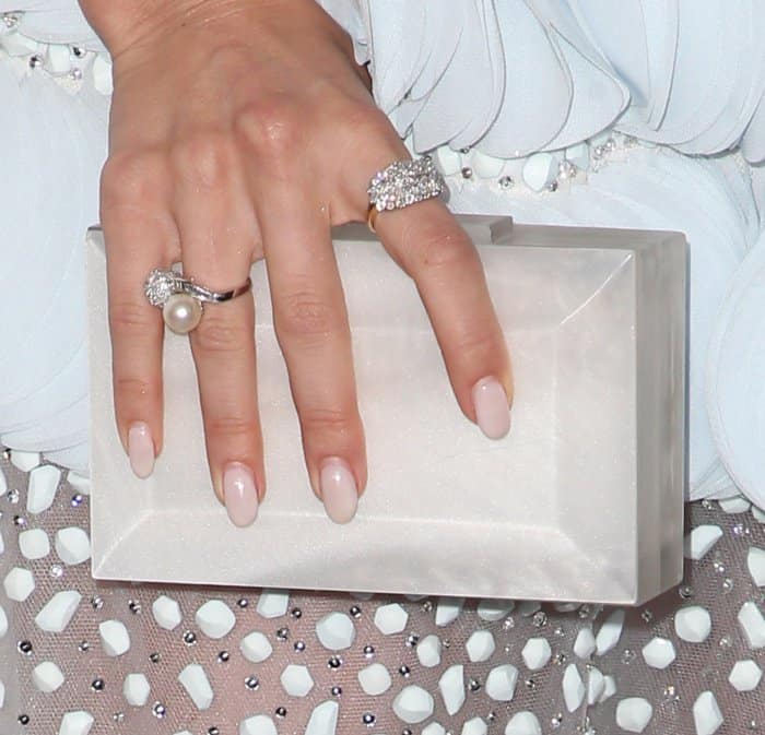 Julianne Hough complemented her elegant look with a soft nude manicure, a pearl-accented ring, and a sparkling diamond band, perfectly paired with a sleek box clutch