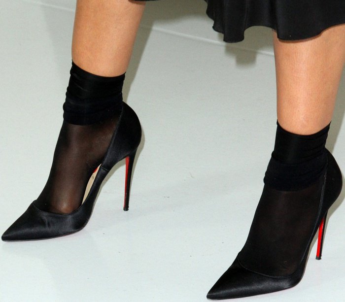 Tessa Thompson makes a bold style statement by pairing elegant black satin Christian Louboutin pumps with sheer black socks