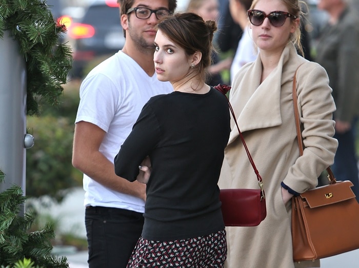 Emma Roberts adds a pop of color to her casual look with a red Coach Legacy Penny crossbody bag, pairing it with a simple black top and printed Band of Outsiders pants