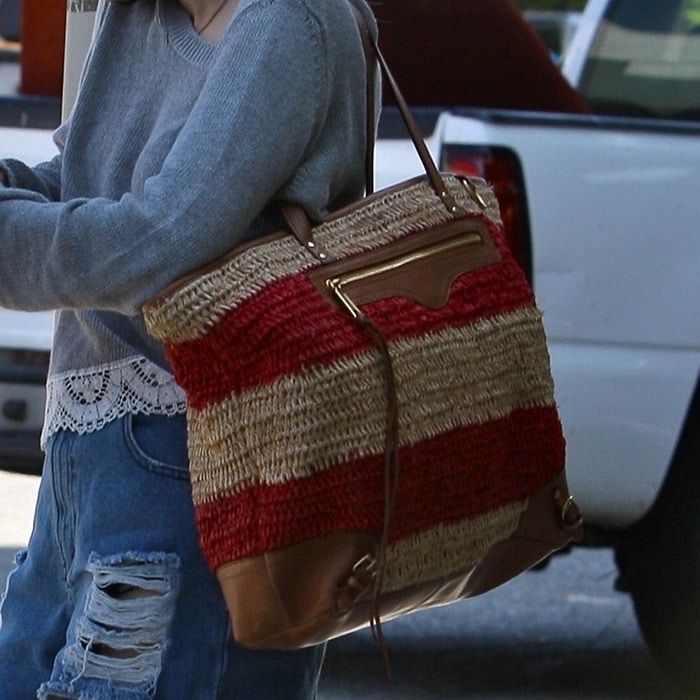 Emma Roberts carries a striped Rebecca Minkoff straw tote, adding texture and a subtle pop of color to her laid-back summer look