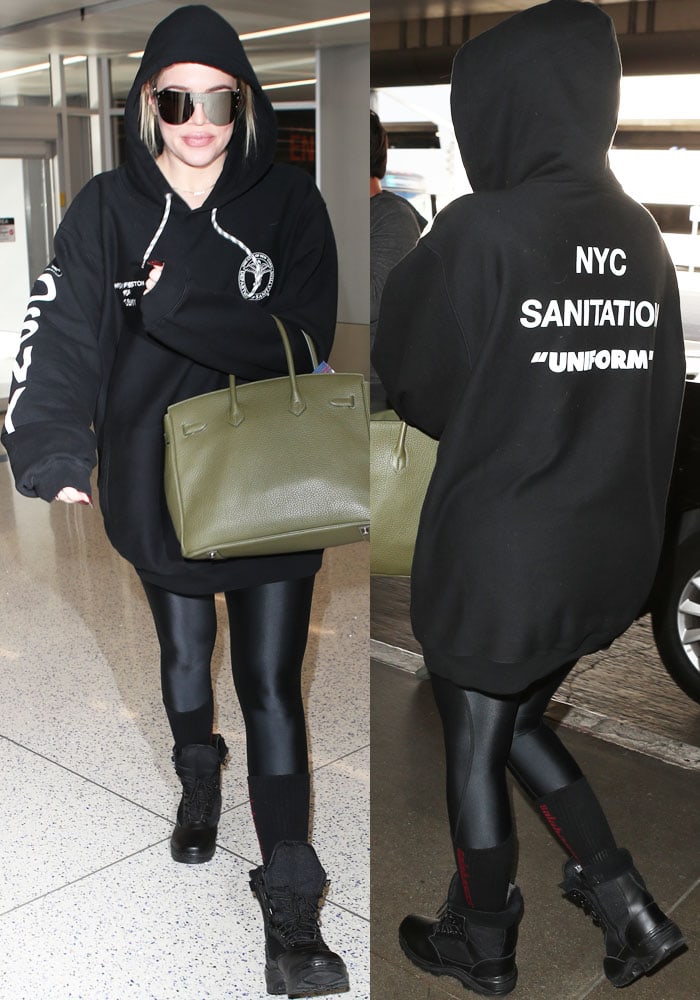 Khloé Kardashian demonstrates the art of relaxed travel style, pairing an oversized Heron Preston 'Uniform' hoodie with sleek black leggings and combat boots