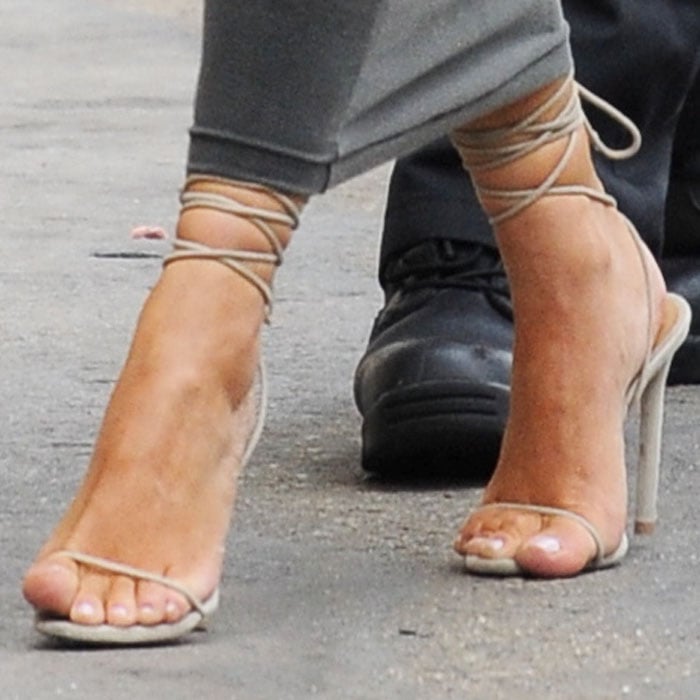 Kim Kardashian wears nude lace-up sandals with wraparound ankle ties, slim toe straps, and stiletto heels