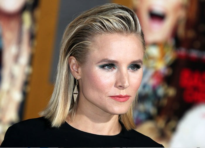 Kristen Bell's polished beauty look is highlighted by her deliberate choice of green eyeshadow, which elegantly complements her coral-toned lips
