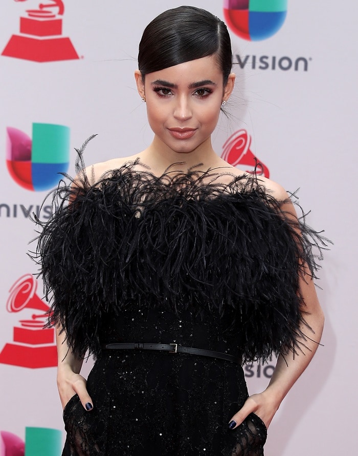 With her hands in her pockets and the textured feather bodice on full display, Sofia Carson exudes confident elegance—her floor-length Elie Saab gown likely concealing the towering heels she favors to enhance her 5ft 4½ frame