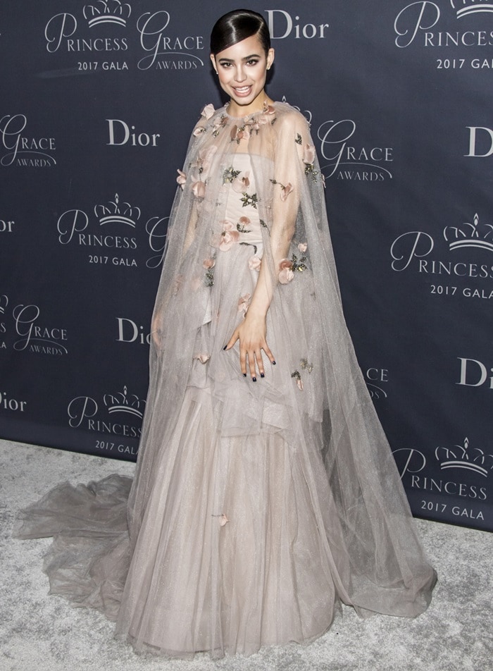 Wrapped in layers of ethereal tulle and blush petals, Sofia Carson’s sweeping Monique Lhuillier gown likely conceals the towering heels she relies on to elevate her petite 5ft 4½ frame