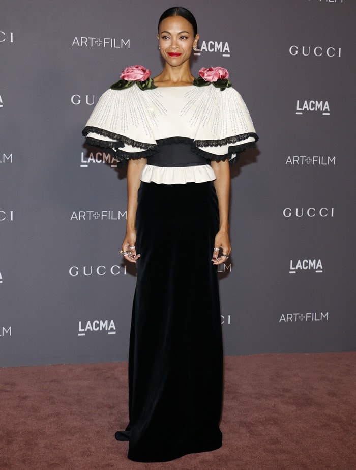 Zoe delivers full red-carpet elegance in her floor-length black velvet Gucci gown topped with a statement floral cape