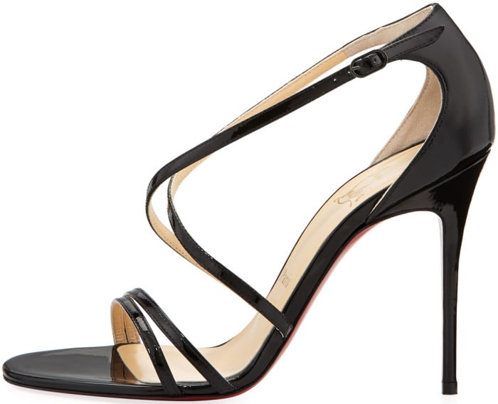 Christian Louboutin’s ‘Gwynitta’ sandal features sculptural crisscross patent-leather straps, a slender adjustable ankle buckle, and the brand’s signature red sole atop a soaring stiletto heel